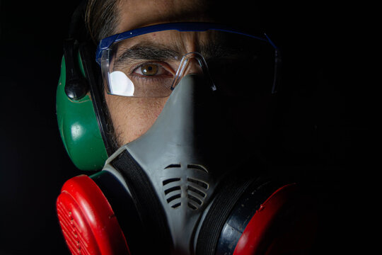 man working and wearing eye protectors, ear protectors and gas mask. on black background. Concept health virus coronavirus epidemic.