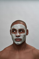 Handsome young african american man looking aside, using facial blackhead removal mask, posing isolated over gray background