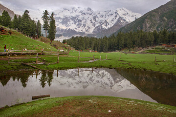 reflection lake landscape with snow mountains green valley and clouds in the sky, fairy meadows and nanga parbat reflection in calm water 