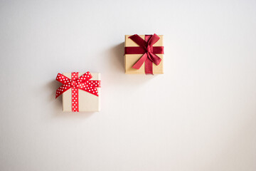 Two small gift boxes with tied decorative bow and red ribbon