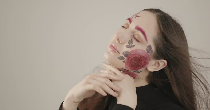 young girl elegantly touches her face with her hands while posing for the camera in the studio