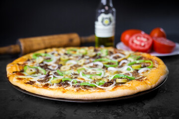 Pizza deliciosa com ingredientes na mesa de madeira com fundo escuro.