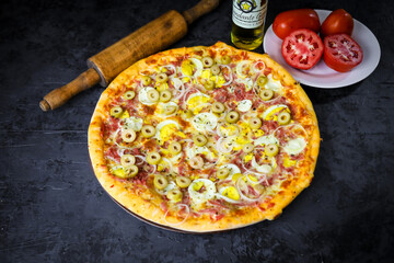 Pizza deliciosa com ingredientes na mesa de madeira com fundo escuro.