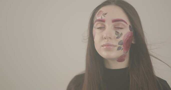 beautiful girl with brightly painted face is thrilled by shooting in the studio
