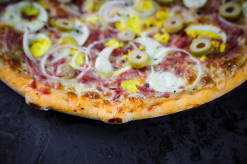 Pizza deliciosa com ingredientes na mesa de madeira com fundo escuro.