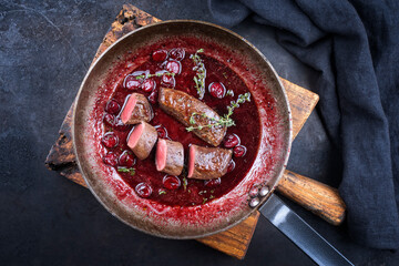 Traditional wild hare back filet braised with wild berries and cherry relish souse served as top view in rustic frying pan on an old wooden board © HLPhoto