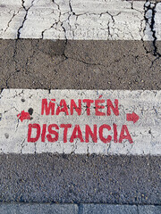 Social distancing sign (Manten Distancia) painted on the ground to advise pedestrians to keep social distance during the Coronavirus (COVID-19) pandemic, Oviedo, Spain.