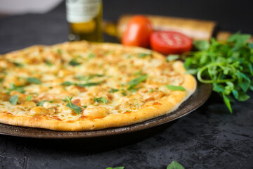 Pizza deliciosa com ingredientes na mesa de madeira com fundo escuro.