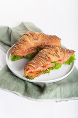 Croissant Sandwich with salmon and salad leaves