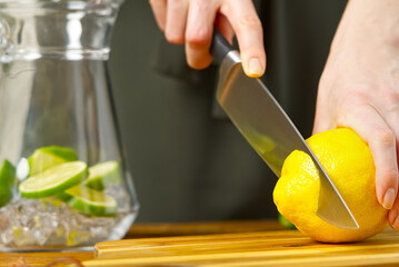 Woman cutting lemon in kitchen, lemon water, Refreshing Water with lime and lemon, healthy eating concept
