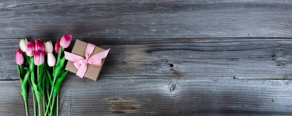 Top view of pink tulips and a giftbox on rustic wood for Mothers Day concept