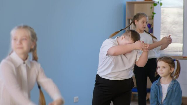 active lifestyle, overweight boy kid with down syndrome dancing with a group of healthy children during a dance lesson closeup