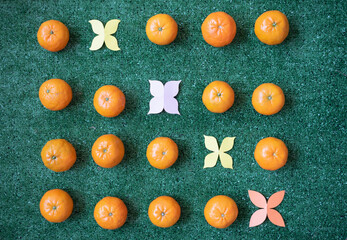 Tangerines and paper flowers on  green background