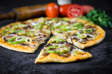 Pizza deliciosa com ingredientes na mesa de madeira com fundo escuro.