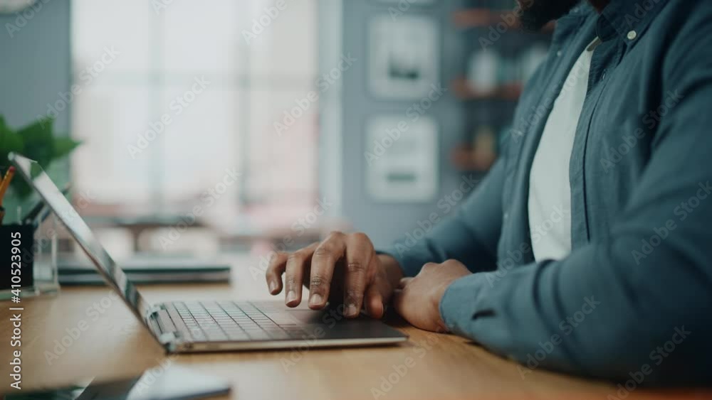 Poster close up on hands of a black african american man working on laptop computer while sitting behind de
