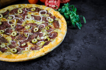 Pizza deliciosa com ingredientes na mesa de madeira com fundo escuro.