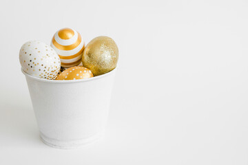 Easter golden decorated eggs in bucket on white background. Minimal easter concept. Happy Easter card with copy space for text