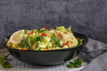 Salad. Spring vegetable salad. Fresh vegetable salad with tomatoes, apple, nuts, seeds and lemon. Olive oil pouring into bowl of salad