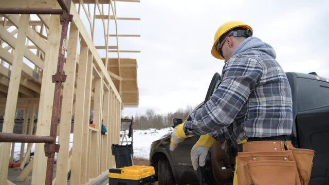 Construction Worker Wearing Safety Working Gloves in Front of Newly Constructed House