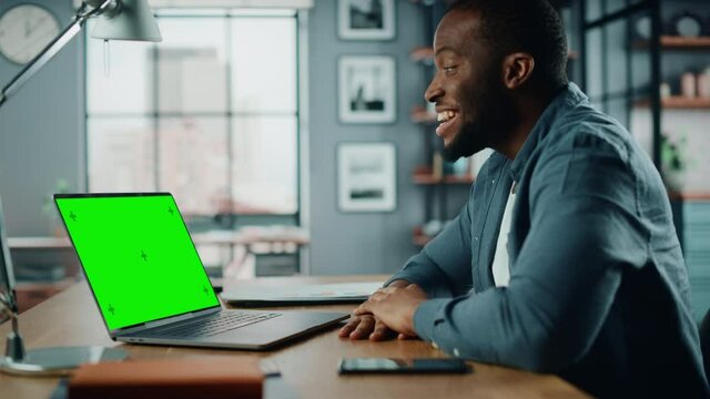 Handsome Black African American Specialist Chatting on Video Call on Laptop with Green Screen Mock Up Display at Home Living Room. Freelance Man Chatting to Clients Over Internet on Social Networks.
