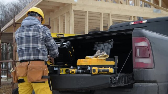 Caucasian Contractor Worker Preparing His Construction Tools on the Pickup Bed. Industrial Theme