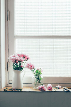 Pastel pink flowers on a vintage window sill.