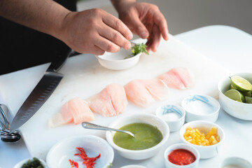 Obraz na płótnie Canvas Closeup de manos de un chef preparando una receta de pescado