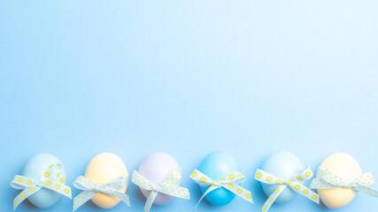 Easter background. Colorful egg with tape ribbon on pastel blue background in Happy Easter decoration. Spring holiday top view concept.