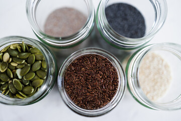 seed jars with sesame poppy pupmkin chia and flax seeds as important nutrient sources for nutrition shot on white background