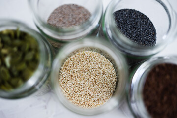 seed jars with sesame poppy pupmkin chia and flax seeds as important nutrient sources for nutrition shot on white background