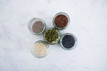 seed jars with sesame poppy pupmkin chia and flax seeds as important nutrient sources for nutrition shot on white background