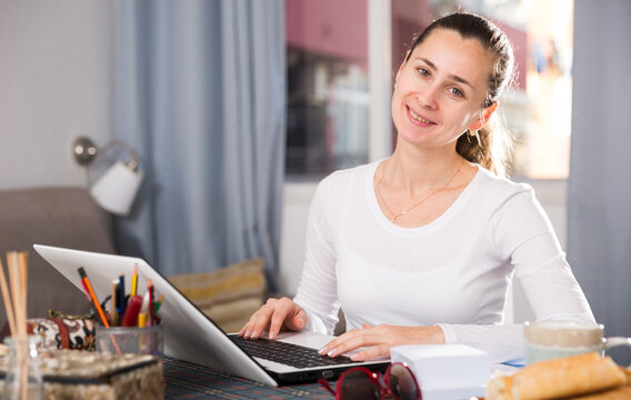 Smiling girl sitting at table at home calculating domestic finances and bills. High quality photo