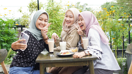 Asian hijab woman group selfie in cafe with friend