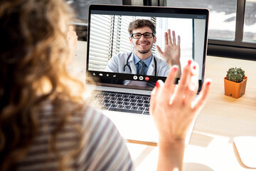 Female patient meeting with doctor via video call on laptop computer at home, medical online...