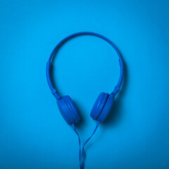 Stylish blue headphones with a wire on a blue background.