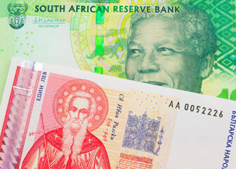 Fototapeta premium A macro image of a shiny, green 10 rand bill from South Africa paired up with a red and white one lev bank note from Bulgaria. Shot close up in macro.