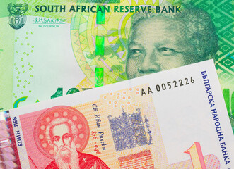 A macro image of a shiny, green 10 rand bill from South Africa paired up with a red and white one lev bank note from Bulgaria.  Shot close up in macro.