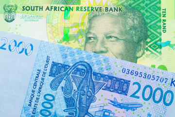 A macro image of a shiny, green 10 rand bill from South Africa paired up with a blue, two thousand West African franc bank note.  Shot close up in macro.