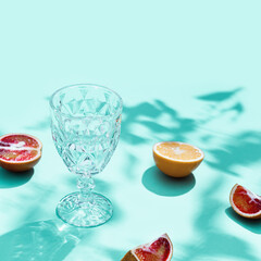 Composition with slices grapefruit, red orange, lemon and drink glass on turquoise color. Summer time flat lay with daylight.
