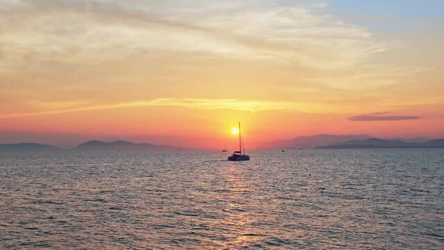 The sea view of a sailing boat in the background at sunset, on Paralia Flisvos, Athens, Greece