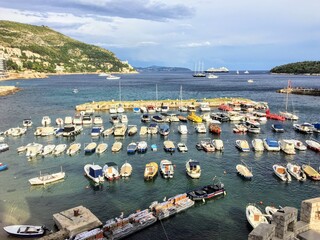A view of a marina full of rows of many boats anchored side by side outside of the Walls of Dubrovnik on the Adriatic Sea in Dubrovnik, Croatia.