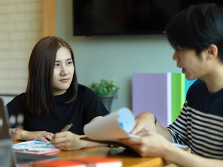 Two office worker discussing on their work with paperwork on clipboard