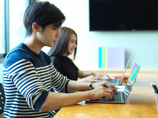 Two office workers working with laptops on meeting table