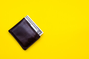 Dollar note in brown leather pocket on yellow blackground
