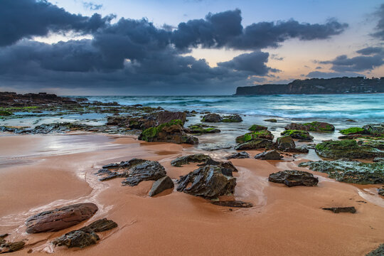 Grey Clouds And Rocky Foreground Overcast Sunrise At The Beach