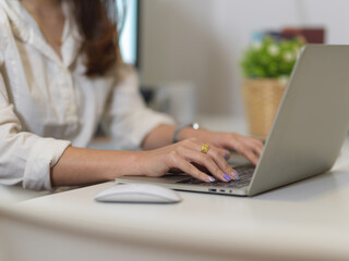 Female hand typing on laptop keyboard on white office desk