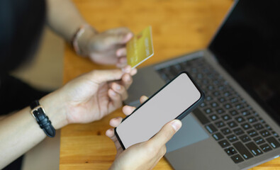 Hands holding smartphone and credit card while online paying on smartphone