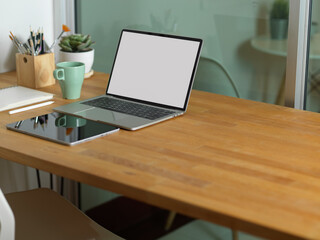 Workspace with laptop, tablet, supplies and copy space on wooden table