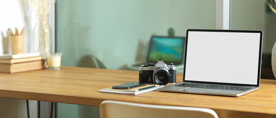 Worktable with laptop, camera, stationery and copy space on the table