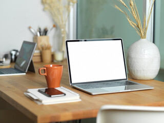 Close up view of workspace with laptop, paperwork, smartphone and cup on table